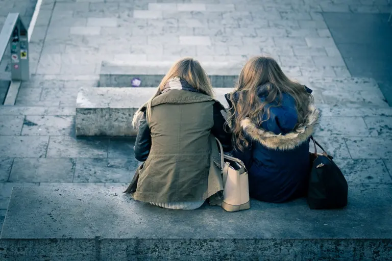 Two friends sitting together on a step